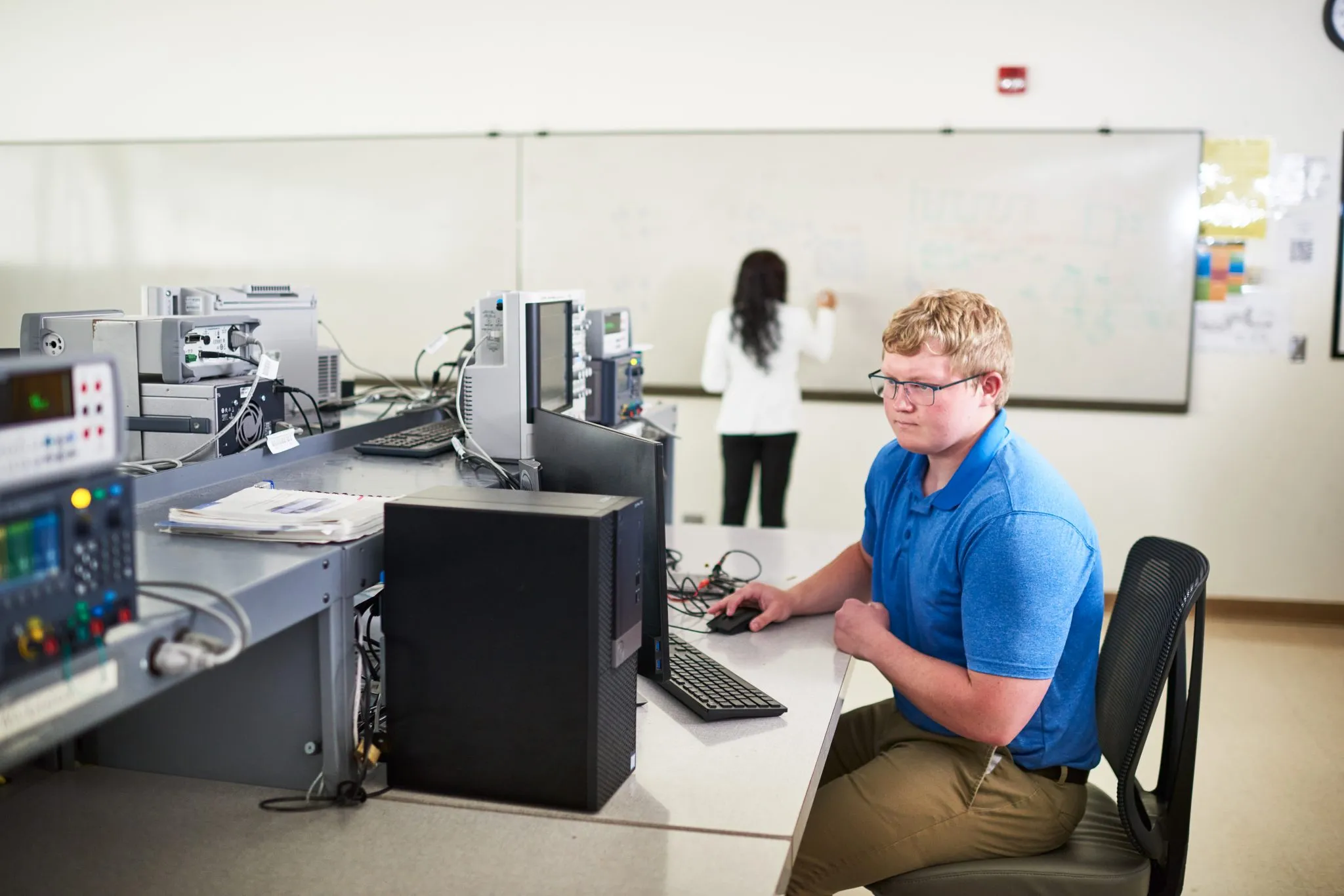 Student working on computer in white lab room.